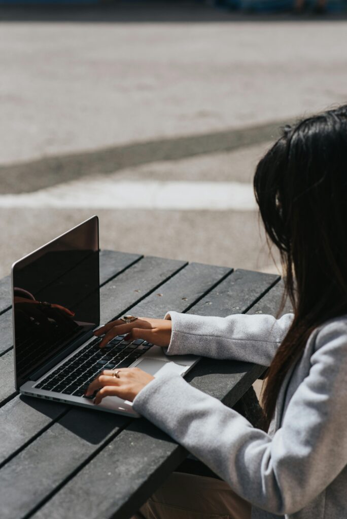 Vrouw die buiten op een tafel surft op het internet via laptop.